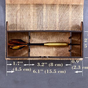 May include: A wooden box with a compartment for storing darts. The box is 6.1 inches long, 3.2 inches wide, and 2 inches tall. The box is made of light brown wood and has a natural finish.