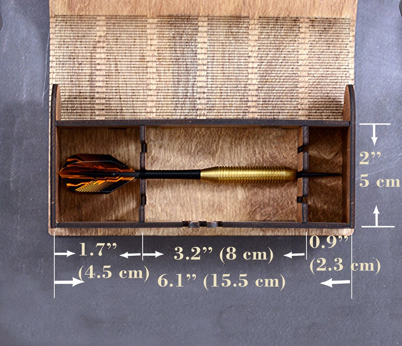 May include: A wooden box with a compartment for storing darts. The box is 6.1 inches long, 3.2 inches wide, and 2 inches tall. The box is made of light brown wood and has a natural finish.