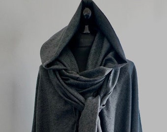 May include: A dark gray hooded cape with a matching scarf tied at the front. The cape is made of a soft, textured fabric and hangs to the floor. The hood is large and drapes over the shoulders.