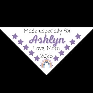 May include: White triangular bandana with purple stars and a rainbow design. The text reads "Made especially for Ashlyn Love, Mom 2025".