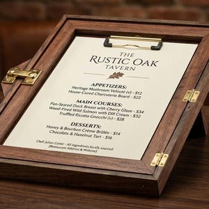 May include: A wooden menu holder with brass hinges and a clip, displaying a menu from "The Rustic Oak Tavern." A glass of whiskey with a large ice sphere sits beside it. The menu lists appetizers, main courses, and desserts.