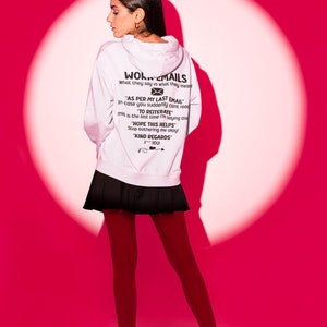 May include: A white hoodie with a black graphic print that says "Work Emails" and includes a message about "As per my last email" and "To reiterate". The model is wearing a black skirt and red tights.