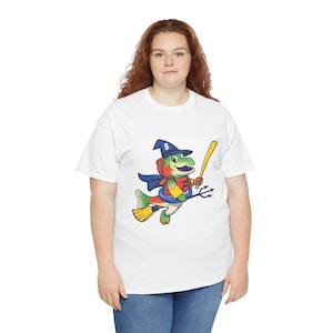 May include: White t-shirt featuring a cartoon fish character wearing a witch hat, cape, and holding a baseball bat and trident. The fish has a colorful design with green, red, yellow, and blue accents. The letter "S" is on the hat.