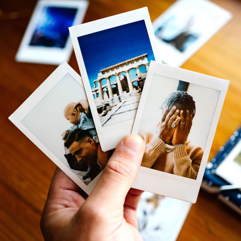May include: Three instant photos, one showing a white building with columns, another showing a person holding a baby, and the last showing a person covering their face with their hands.