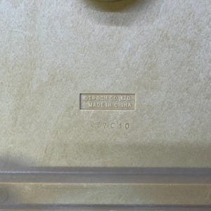 May include: Close-up of a beige plastic surface with the embossed text "EPOCH CO., LTD. MADE IN CHINA" and the numbers "A27 C10". The surface has a slightly textured appearance.