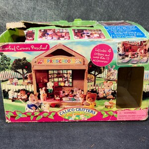 May include: A boxed Calico Critters Cloverleaf Corners Preschool playset. The box features a colorful illustration of a preschool with animal figures, a fence, and trees. The box text includes "Includes 4 critters and more than 15 accessories!"