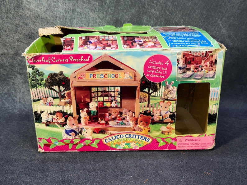 May include: A boxed Calico Critters Cloverleaf Corners Preschool playset. The box features a colorful illustration of a preschool with animal figures, a fence, and trees. The box text includes "Includes 4 critters and more than 15 accessories!"