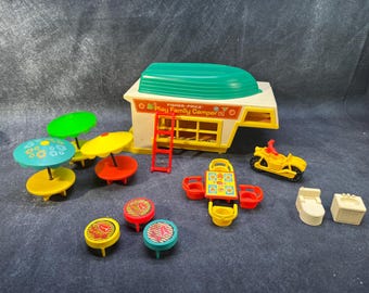 May include: A vintage Fisher-Price Play Family Camper set. The set includes a yellow and white camper with a green roof, a red ladder, and various accessories like tables, umbrellas, a motorcycle, and bathroom fixtures. The camper has the text "Fisher-Price Play Family Camper".