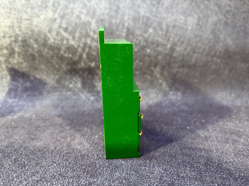 Op de afbeelding: Een groene miniatuurkast met drie lades en goudkleurige knoppen. De kleine kast heeft een rechthoekige vorm en een kleine, verhoogde bovenkant. Het stuk is geschilderd in een heldere, effen groene kleur.