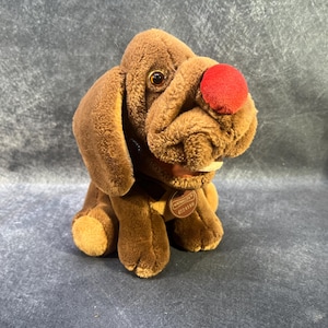 May include: Brown plush dog toy with a red nose and a brown tag that says "Manhatten Toy Co.  #22118".