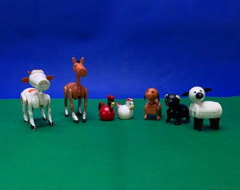 May include: A collection of toy farm animals, including a white and orange cow, a brown horse, a red rooster, a white hen, a brown dog, a black dog, and a white sheep. The toys are arranged on a green surface against a blue background.