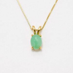 Op de afbeelding: Een gouden ketting met een groene ovale edelsteen hanger.