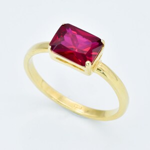 Puede incluir: Un anillo de oro con una piedra preciosa roja rectangular grande.