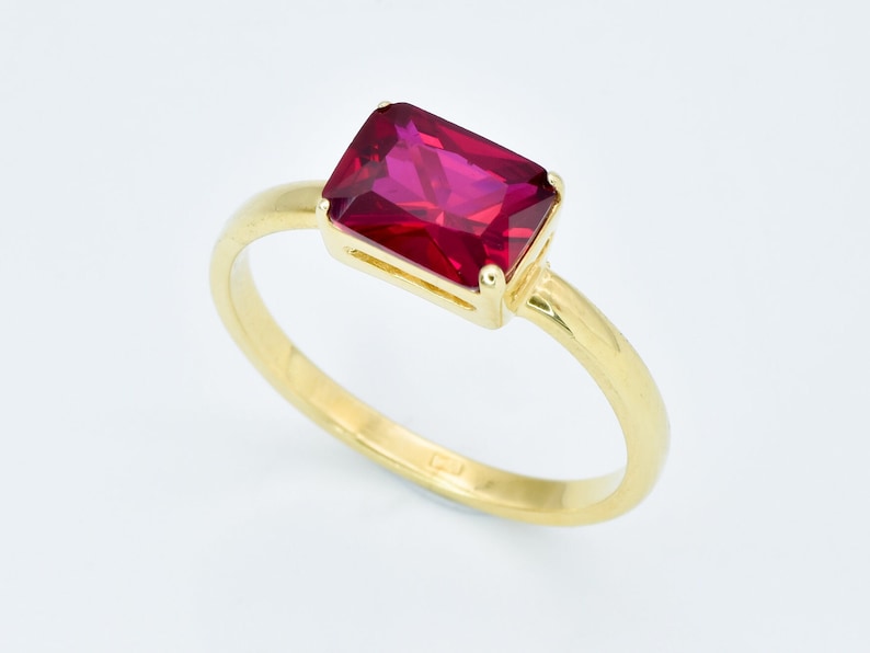 Puede incluir: Un anillo de oro con una piedra preciosa roja rectangular grande.