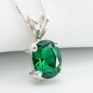 Op de afbeelding: Een zilveren ketting met een groene ovale edelsteen hanger.