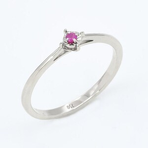 Puede incluir: Un delicado anillo de plata con una peque&ntilde;a piedra preciosa rosa brillante engastada en una sencilla garra. El anillo est&aacute; marcado con "750" en la banda interior.