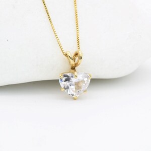 May include: A gold chain necklace with a heart-shaped pendant featuring a clear cubic zirconia stone.