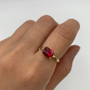 Puede incluir: Un anillo de oro con una piedra rectangular roja.