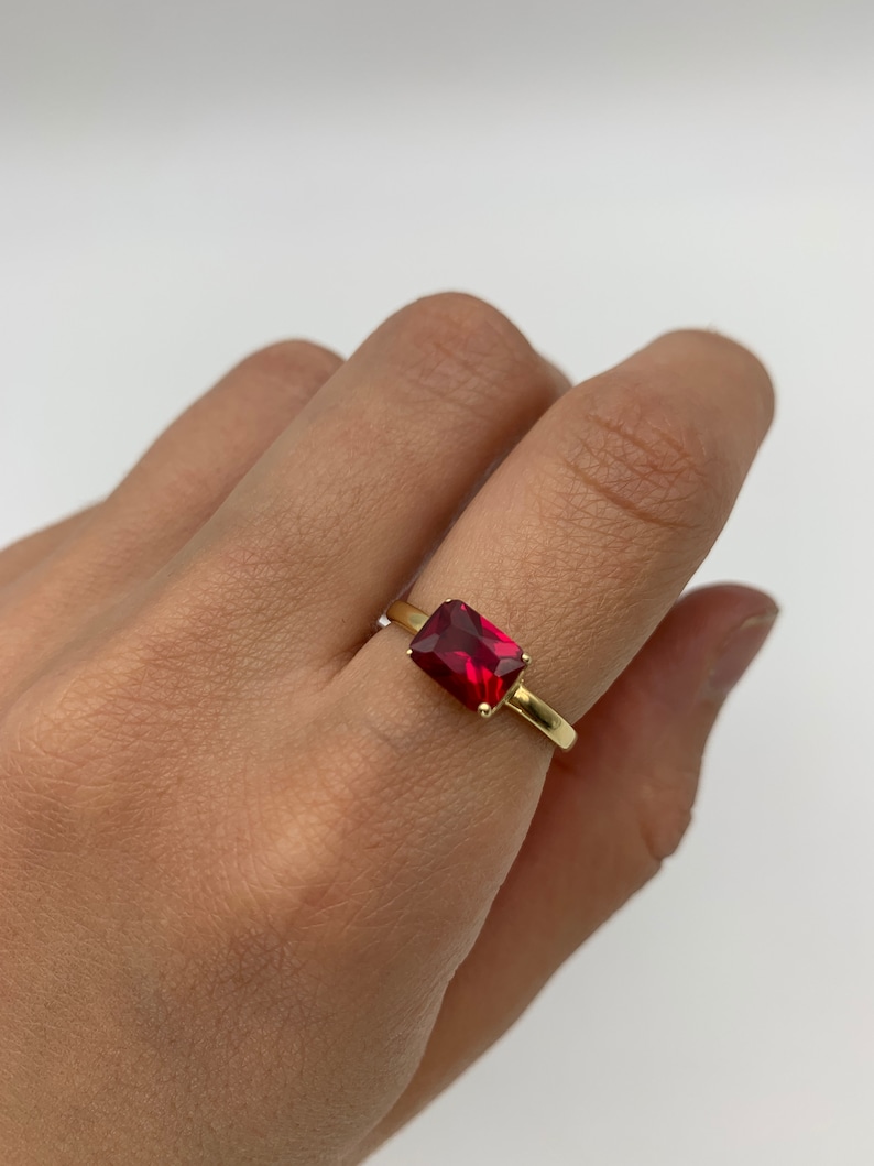 Puede incluir: Un anillo de oro con una piedra rectangular roja.