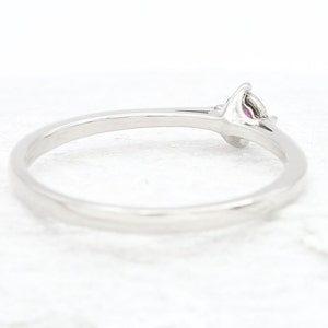 Puede incluir: Un anillo de banda de plata simple con una sola piedra preciosa rosa engastada en una configuraci&oacute;n de garras.