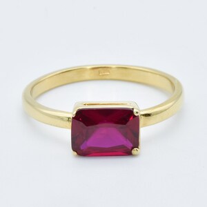 Puede incluir: Un anillo de oro con una piedra preciosa roja rectangular grande.