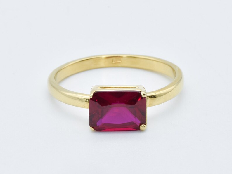 Puede incluir: Un anillo de oro con una piedra preciosa roja rectangular grande.