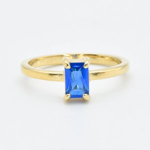 May include: A gold ring with a blue rectangular gemstone.