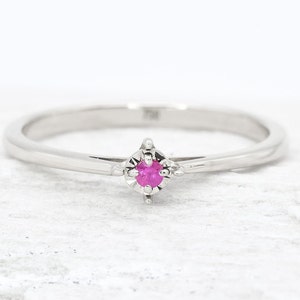 Puede incluir: Un delicado anillo de plata con una peque&ntilde;a piedra preciosa rosa engastada en un engaste de cuatro garras.