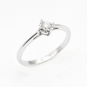 May include: A simple silver band ring with a single round diamond set in a four-prong setting.