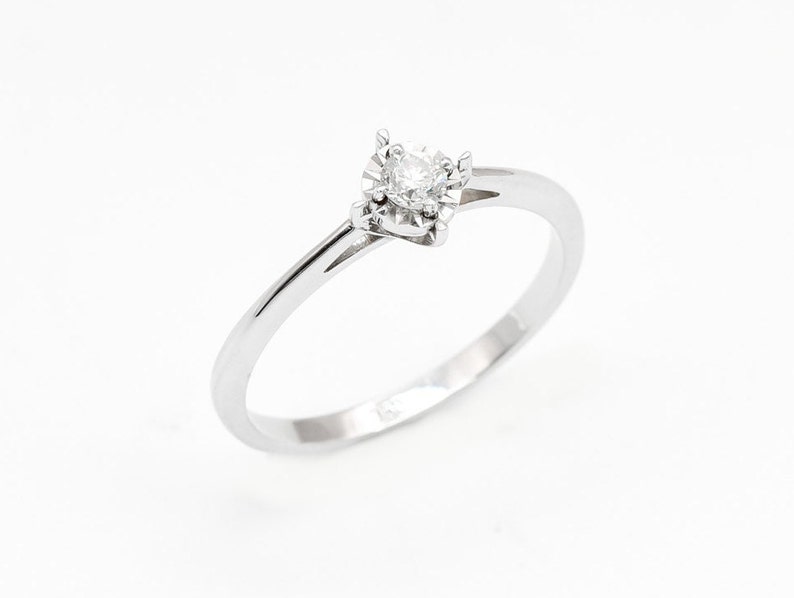 May include: A simple silver band ring with a single round diamond set in a four-prong setting.
