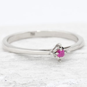 Puede incluir: Un delicado anillo de plata con una peque&ntilde;a piedra de rub&iacute; rosa brillante engastada en un sencillo engaste de cuatro garras.