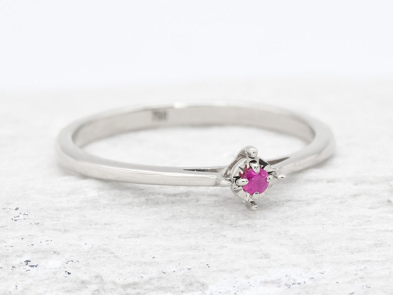 Puede incluir: Un delicado anillo de plata con una peque&ntilde;a piedra de rub&iacute; rosa brillante engastada en un sencillo engaste de cuatro garras.
