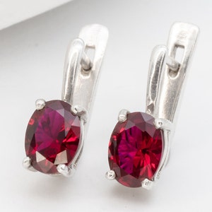 Peut inclure: Une paire de boucles d'oreilles en argent avec des accents de pierres précieuses rouges. Les boucles d'oreilles ont un design simple et élégant et sont parfaites pour un usage quotidien.