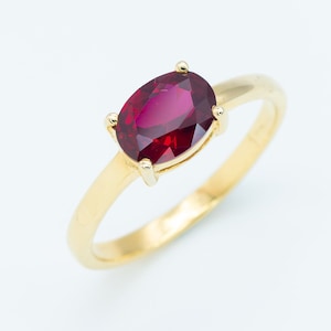 May include: A gold ring with a large oval-shaped ruby gemstone.