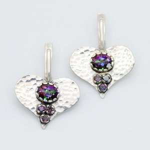 May include: A pair of silver heart-shaped earrings with iridescent gemstones. The earrings have a hammered texture and feature a large oval-shaped gemstone in the centre and three smaller round gemstones below.