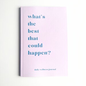 May include: A lavender-colored journal with the text "what's the best that could happen?" and the words "daily wellness journal" at the bottom.