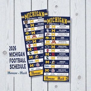 May include: Two rectangular prints displaying the 2026 Michigan Football schedule. The prints feature a navy blue and yellow color scheme with team logos and game dates. The text "Michigan Football 2026" is prominently displayed.
