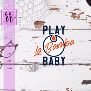 Op de afbeelding: Een witte houten achtergrond met een wit toetsenbord, een bril en een blauwe en oranje afbeelding met de tekst "PLAY La Bamba BABY".