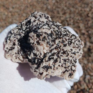 Peut inclure: Gros plan sur une formation rocheuse de couleur blanche et noire. La roche est recouverte de petits cristaux blancs et de points noirs.