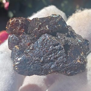May include: A large, dark brown, rough-textured crystal with a metallic sheen. The crystal has a jagged, irregular shape and appears to be a natural mineral specimen.