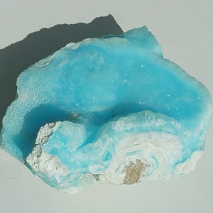 May include: A large, light blue and white crystal with a smooth, rounded surface. The crystal has a unique, layered appearance.