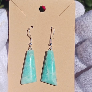 May include: A pair of silver earrings with light green, triangular shaped, gemstone drops.