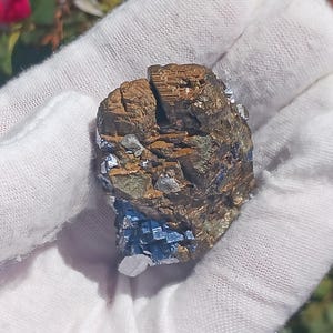 May include: A cluster of pyrite crystals with a metallic gold color and a blue iridescent sheen. The crystals are arranged in a rough, irregular shape.