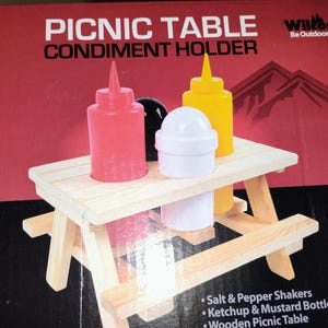 Könnte beinhalten: Ein Wilcor Be Outdoors Picknicktisch-Gewürzhalter-Set in einer roten Schachtel. Das Set enthält einen hellen hölzernen Picknicktisch, eine rote Ketchupflasche, eine gelbe Senfflasche sowie weiße und schwarze Salz- und Pfefferstreuer auf dem Tisch.
