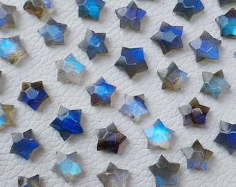 May include: A collection of 30 iridescent blue labradorite star-shaped cabochons. The stones are faceted and have a shimmery, opalescent finish.