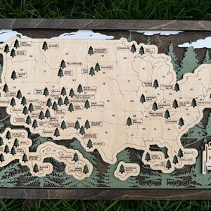 May include: Wooden layered map of the United States with national park names and tree icons. The map is framed in dark wood, with green and white accents. The text "My National Park Adventure" is visible.