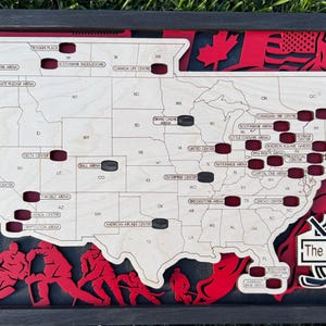 May include: A wooden hockey-themed wall art piece featuring a map of the United States with hockey pucks and arena names. The design includes red and black accents, hockey player silhouettes, and the text "The Smith Family."