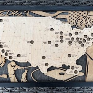 May include: A wooden map of the United States with a baseball theme. The map is in the shape of the country and has holes for each major league baseball team. The map is surrounded by a black frame.