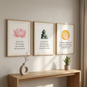May include: Three framed art prints with watercolor images of a pink lotus flower, stacked stones, and a yellow circle. Each print has a different inspirational quote in black text. The frames are light wood.