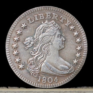 May include: A silver US half dollar coin with the year 1804 and the word "LIBERTY" surrounded by 13 stars. The coin features a bust of Liberty facing right.